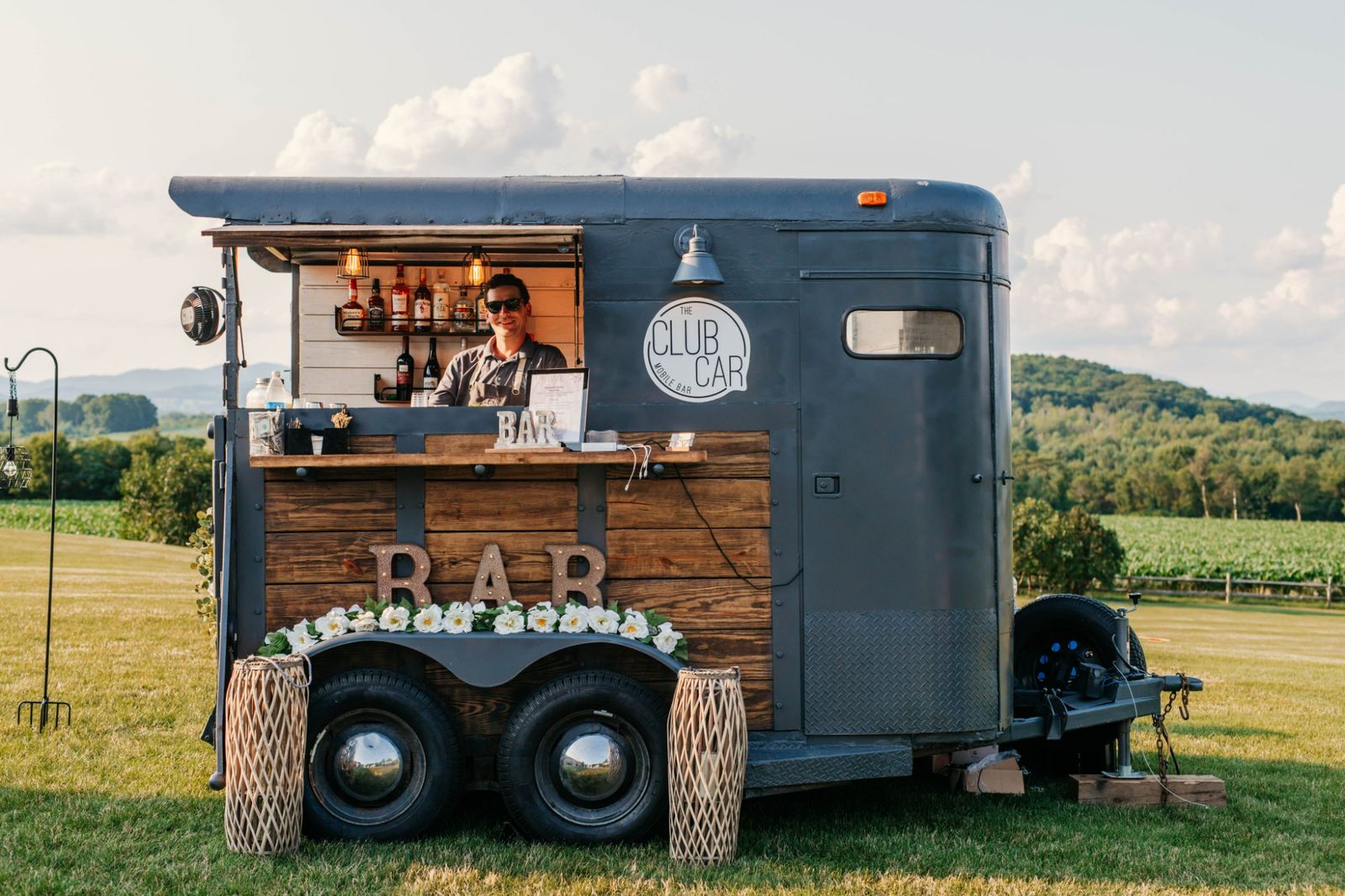 The Club Car mobile bar trailer set up outdoors with a bartender serving drinks